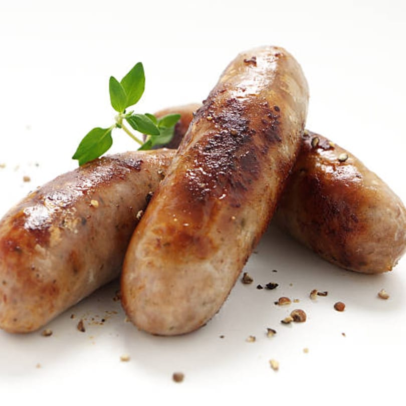Three grilled Italian sausages with herbs and spices on a white background.
